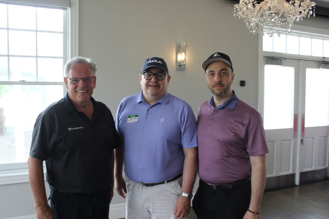 Three attendees posing together indoors during a Techdinamics-sponsored IWLA golf event.