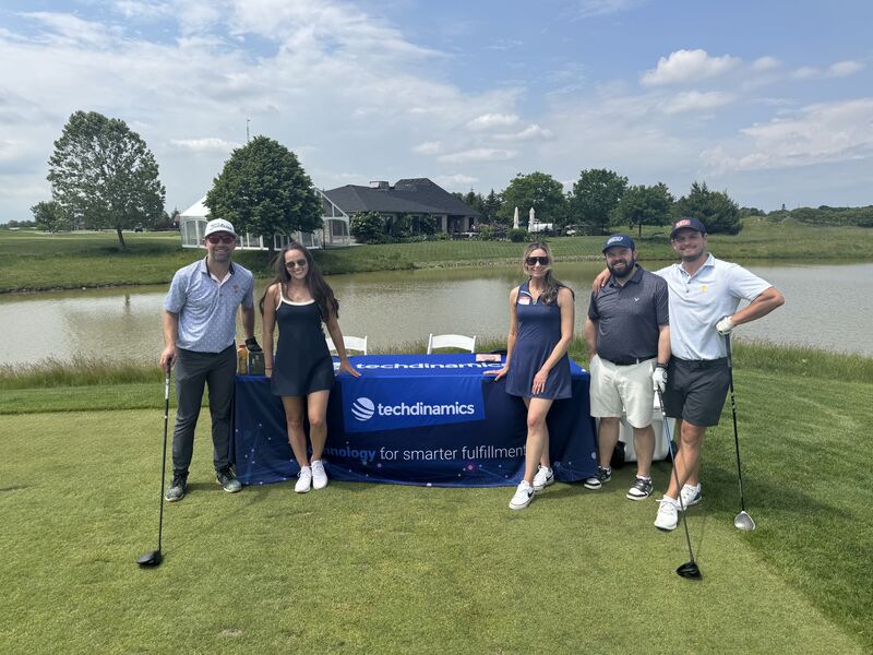 Golf tournament participants gathered around a Techdinamics-branded table at an IWLA networking event.