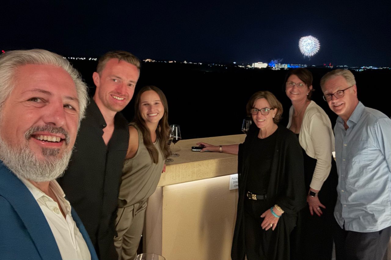 Techdinamics team members and industry guests pose during an evening gathering in Orlando, with fireworks in the background.