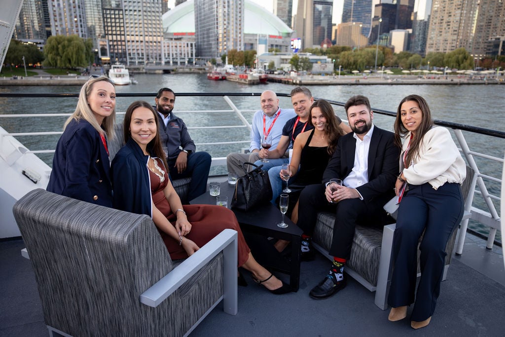 Attendees relax on the yacht deck with the Toronto skyline behind them during the IGNITE 25 waterfront reception.