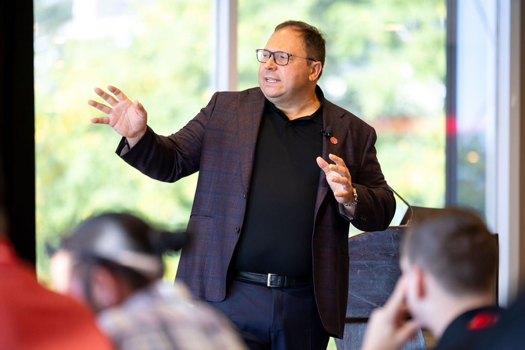 A speaker gestures while addressing attendees during a keynote session at IGNITE 25, Techdinamics' 2025 user conference.