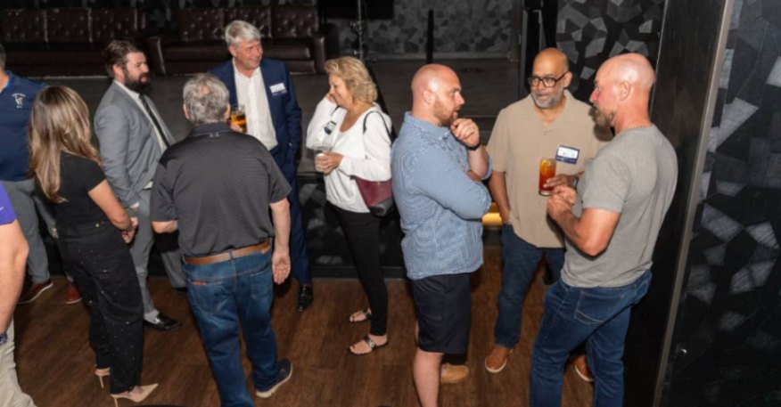 Event attendees gathered around a cocktail table discussing business topics.