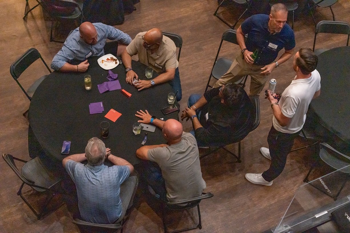 Attendees gathered around a table networking and chatting during a Techdinamics-sponsored industry event.