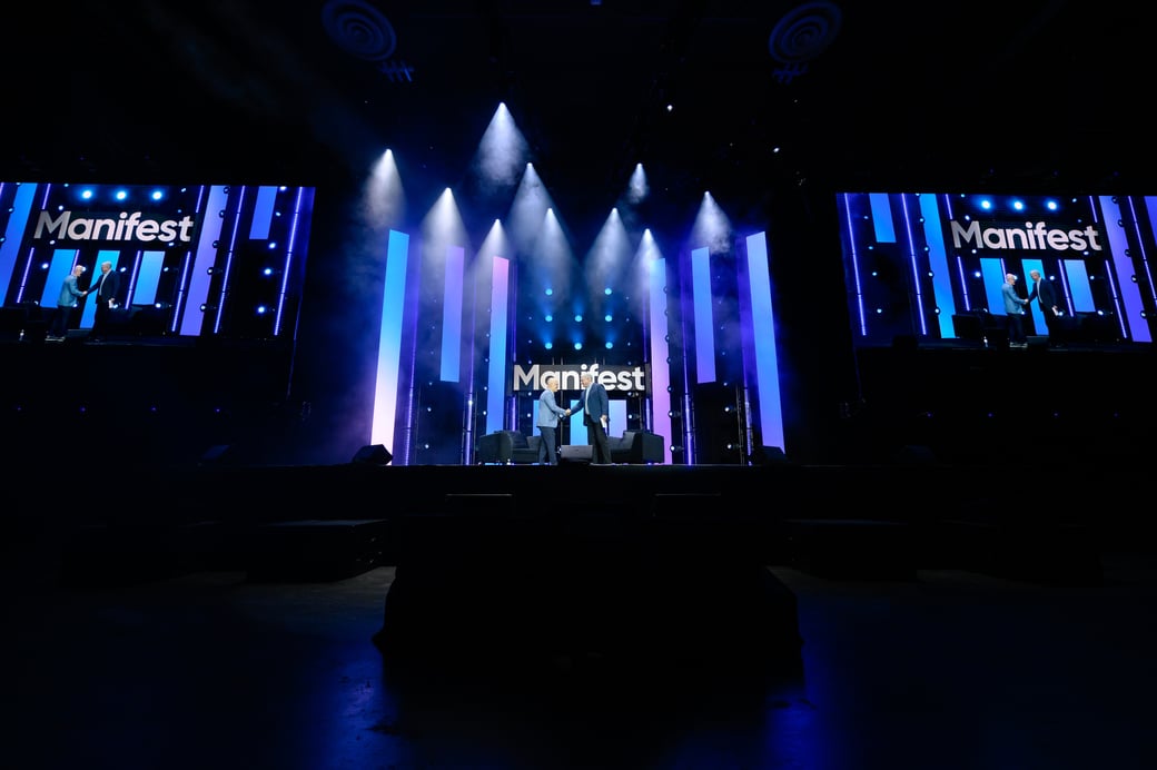 Two people shaking hands onstage at Manifest