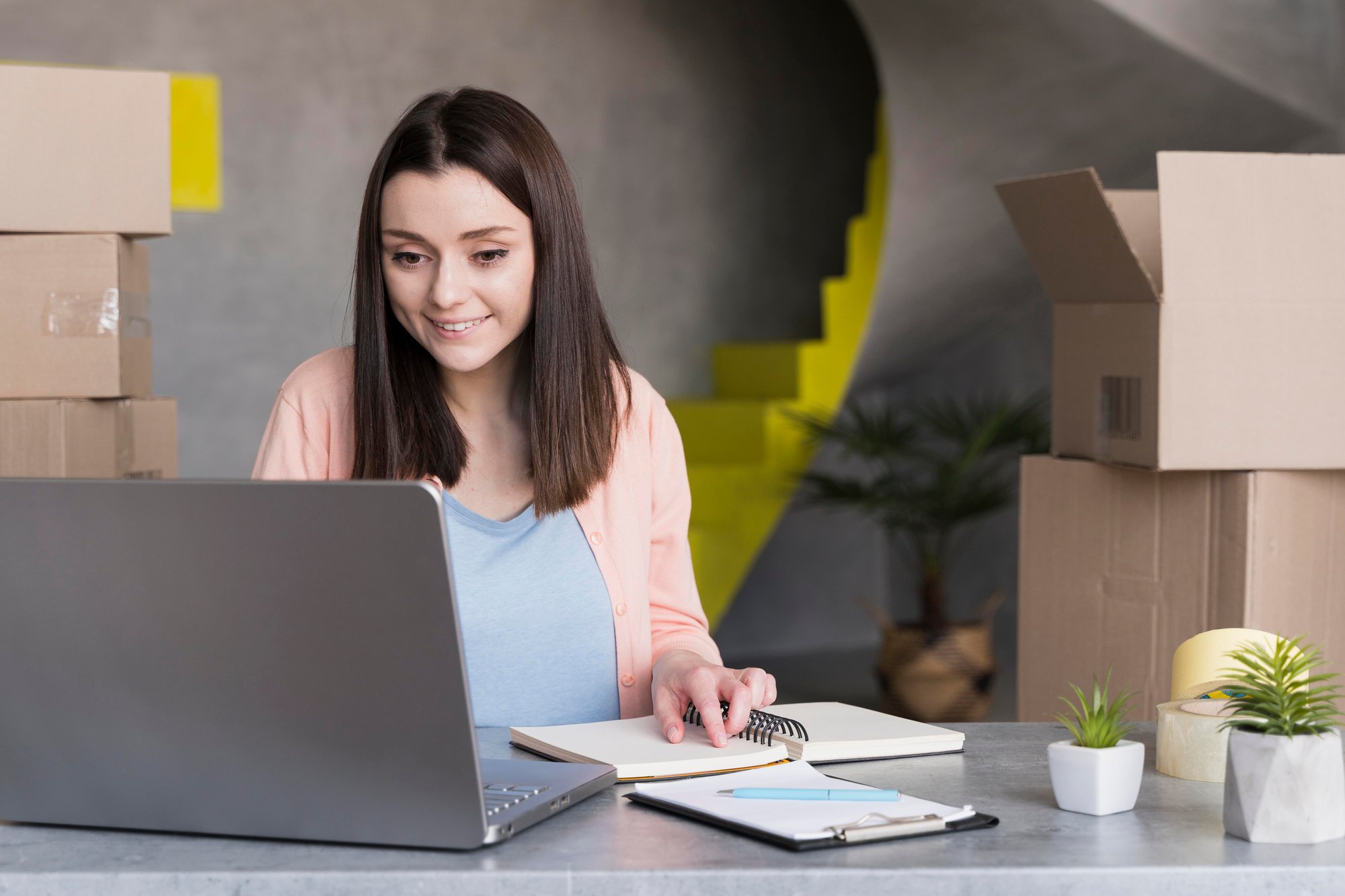 front-view-woman-working-laptop-with-boxes-back